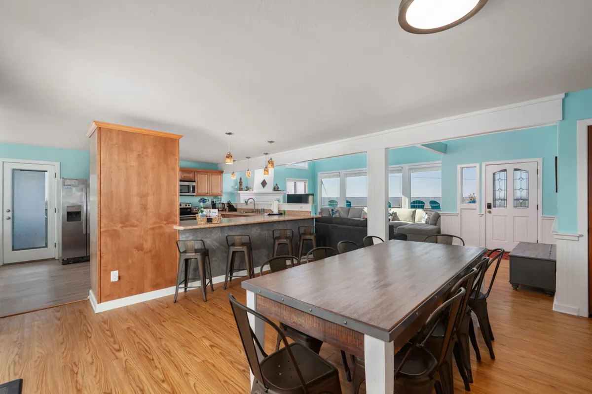 A bright, open dining area with a large dining table perfect for hosting family feasts. The space flows seamlessly into a modern kitchen with an island, and windows offer beautiful exterior views, blurring the line between indoors and out.
