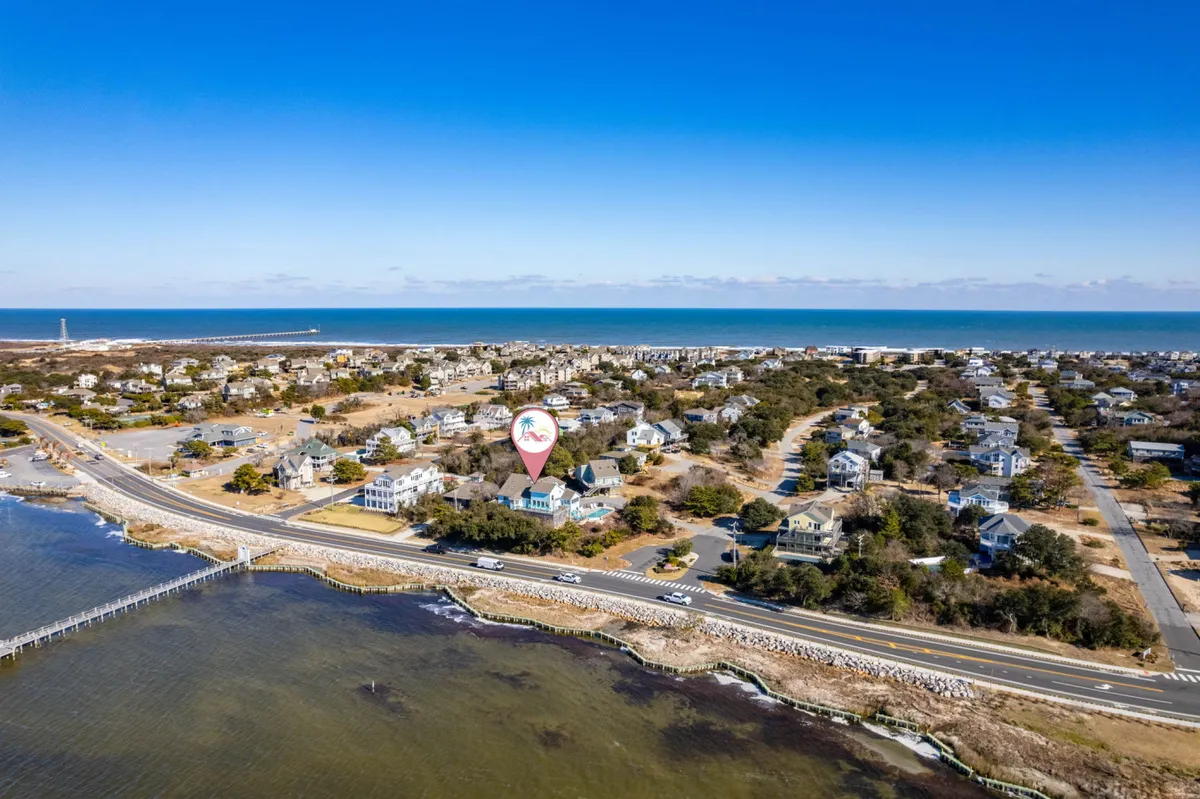 A picturesque exterior shot featuring sweeping views of the ocean, the surrounding residential area, and a main road leading toward the water. The image conveys easy access to the beach and open, walkable surroundings—ideal for outdoor activities like morning runs or strolls with your dog.