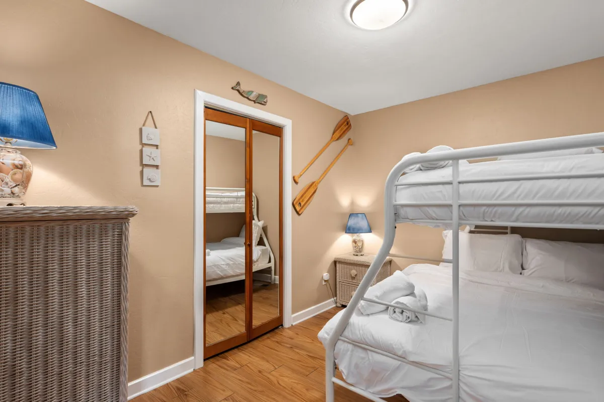 A playful yet comfortable bunk room, featuring a cozy bunk bed, blue lamp, decorative oars, and a mirror. Soft natural light and thoughtful decor create a welcoming setting ideal for kids or groups, aligning with the section’s emphasis on flexibility and family-oriented design.